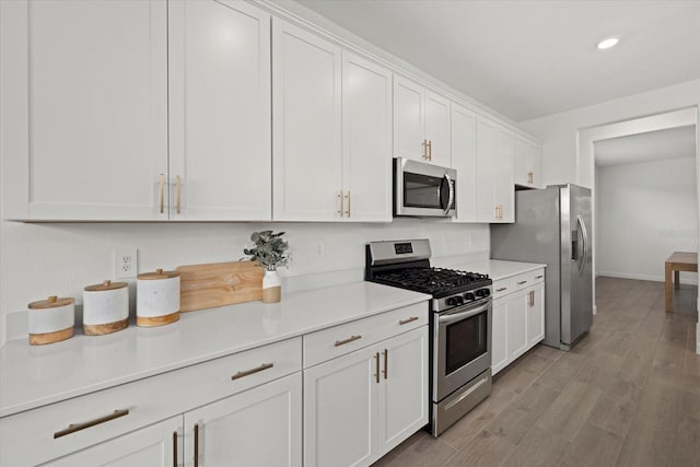 kitchen featuring light wood finished floors, white cabinets, appliances with stainless steel finishes, light countertops, and recessed lighting