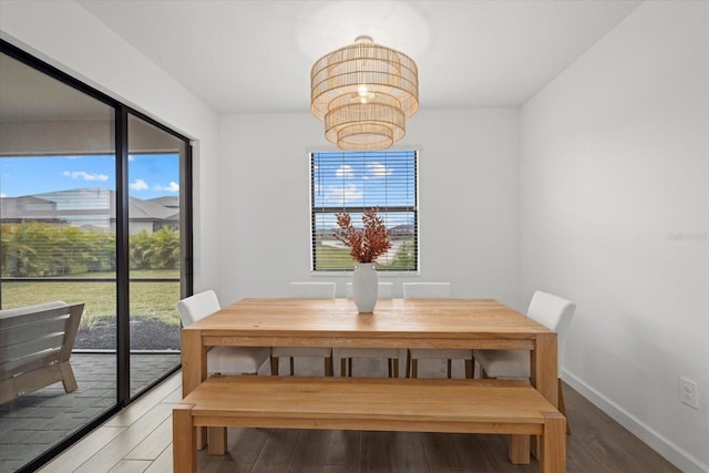 dining room featuring wood finished floors, baseboards, and an inviting chandelier