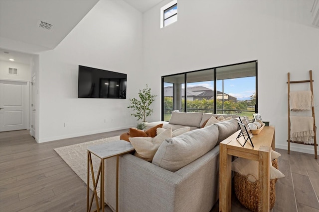 living area featuring baseboards, visible vents, and wood finished floors