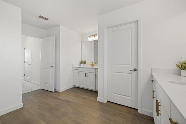 bathroom with vanity, wood finished floors, visible vents, and baseboards