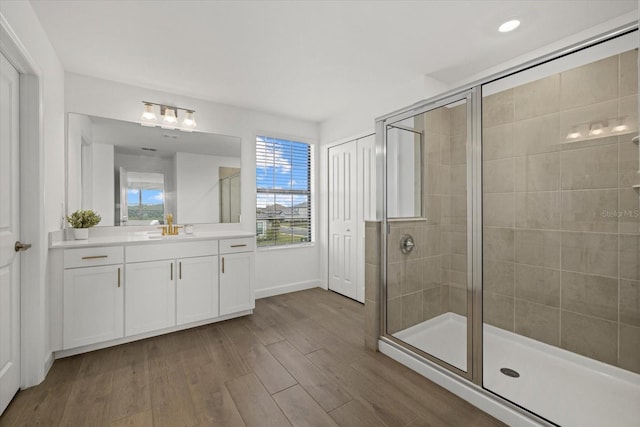 bathroom featuring wood finished floors, vanity, baseboards, a closet, and a stall shower