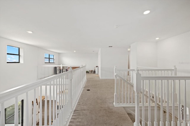 hall with recessed lighting, light colored carpet, and an upstairs landing