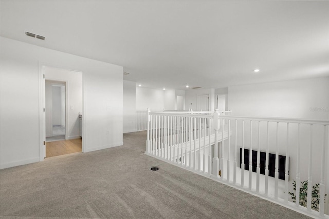 empty room featuring light colored carpet, visible vents, baseboards, and recessed lighting