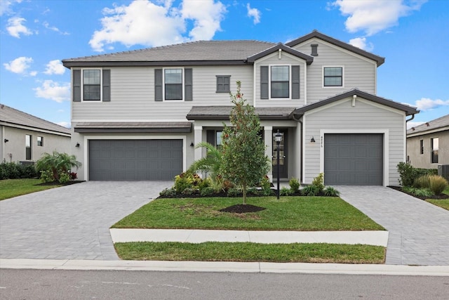 traditional-style home featuring a garage, decorative driveway, and a front yard