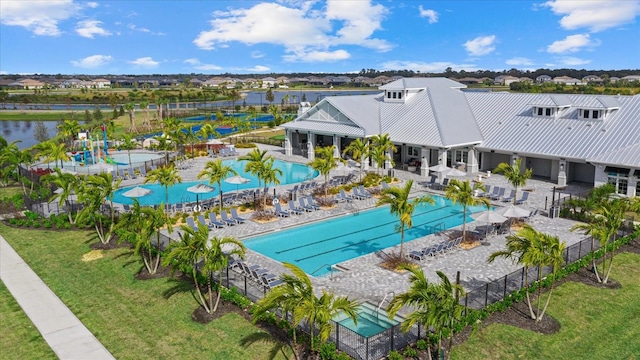 community pool with a patio, a water view, and fence