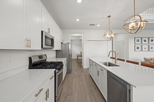 kitchen featuring appliances with stainless steel finishes, white cabinets, a sink, and light countertops