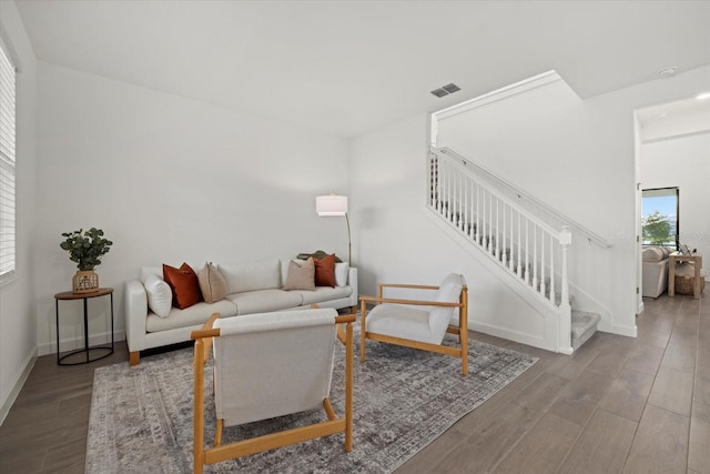 living room with stairs, wood finished floors, visible vents, and baseboards