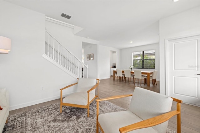 sitting room with recessed lighting, wood finished floors, visible vents, baseboards, and stairs