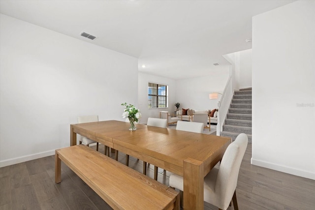 dining space with dark wood-style flooring, stairway, visible vents, and baseboards