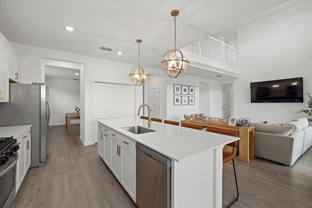 kitchen featuring a sink, white cabinets, light countertops, appliances with stainless steel finishes, and an island with sink