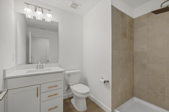 bathroom featuring baseboards, visible vents, wood finished floors, a tile shower, and vanity