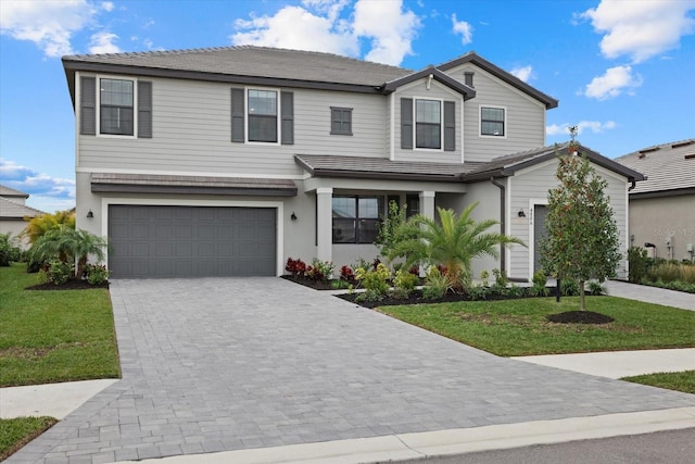 traditional-style home with decorative driveway, an attached garage, and a front lawn