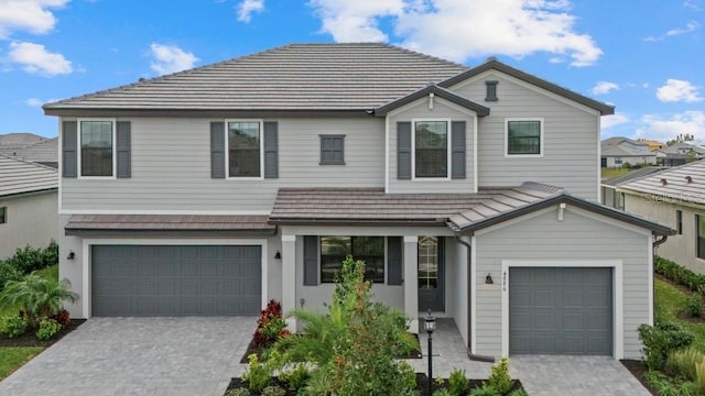 view of front of house with decorative driveway, an attached garage, and a tile roof