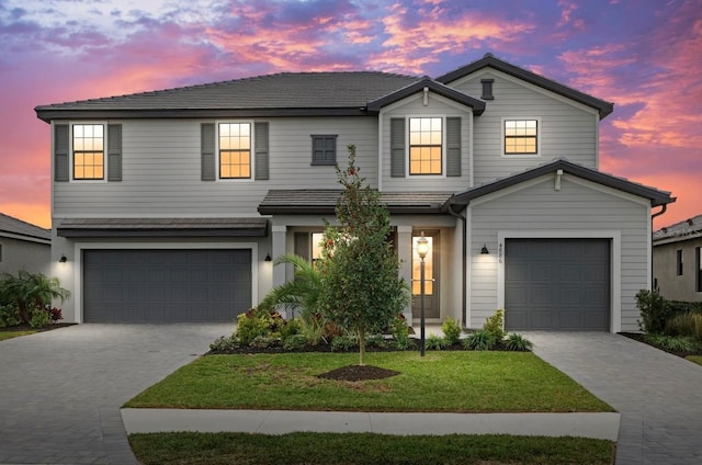 traditional-style home featuring a garage, decorative driveway, and a front lawn