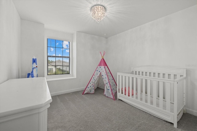 bedroom featuring a nursery area, an inviting chandelier, carpet flooring, and baseboards