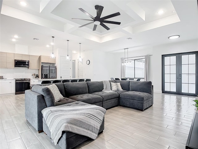 living room with ceiling fan, a tray ceiling, french doors, and coffered ceiling