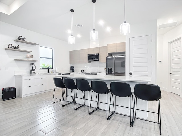 kitchen with appliances with stainless steel finishes, a kitchen bar, hanging light fixtures, and sink