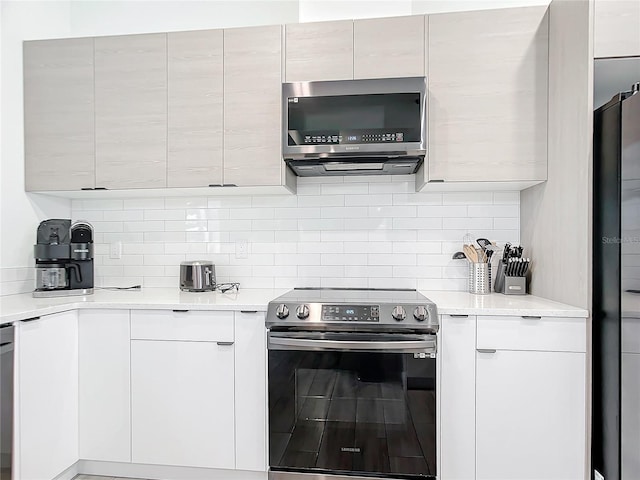 kitchen with tasteful backsplash, white cabinets, and appliances with stainless steel finishes