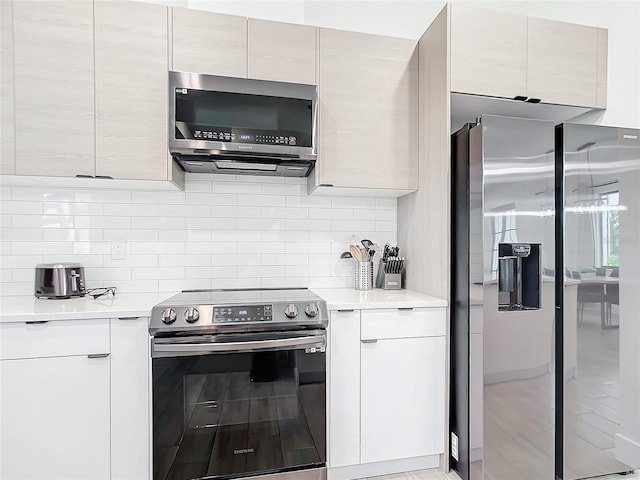 kitchen with white cabinets, decorative backsplash, and appliances with stainless steel finishes