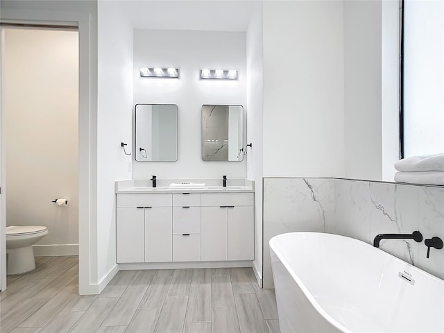 bathroom featuring toilet, a bath, and vanity