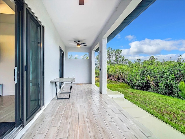 wooden terrace featuring ceiling fan, a yard, and a patio