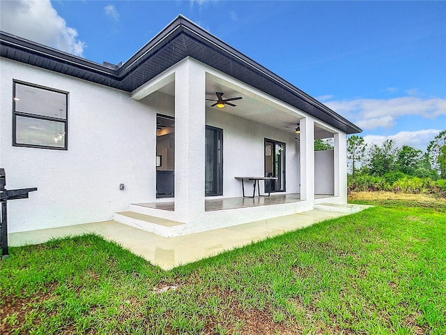 rear view of property featuring ceiling fan and a yard