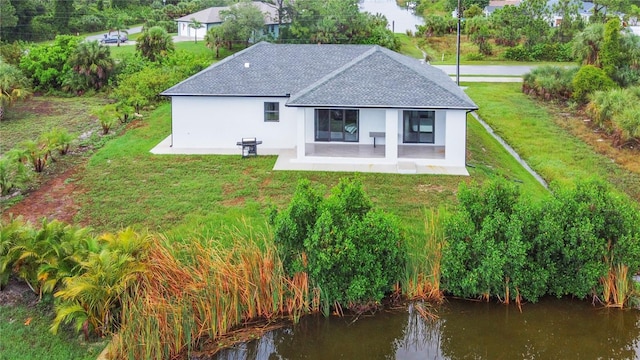 back of property featuring a patio area, a yard, and a water view