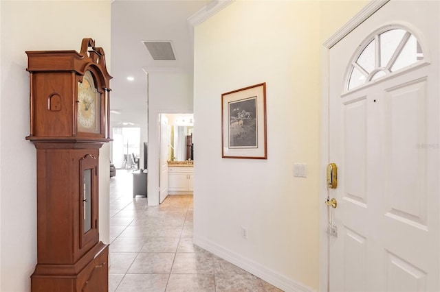 tiled foyer entrance featuring crown molding