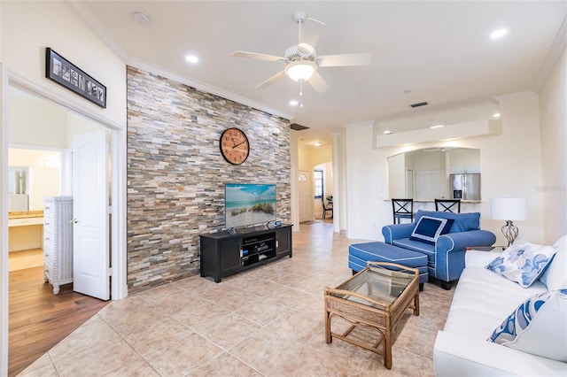 tiled living room with ceiling fan and crown molding