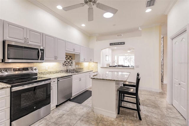 kitchen with a kitchen bar, appliances with stainless steel finishes, white cabinetry, and a center island