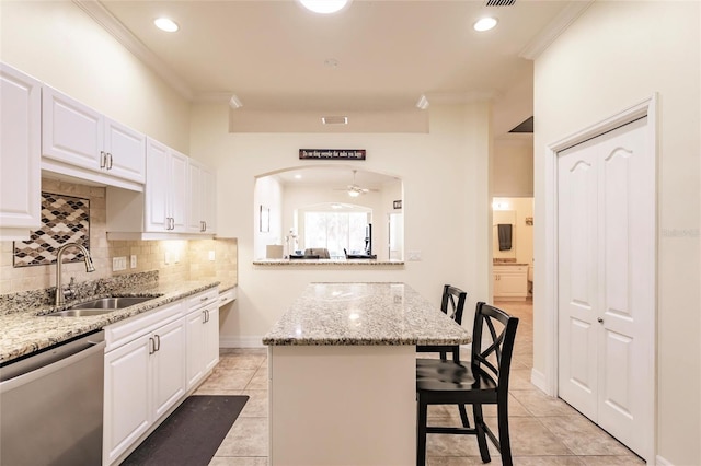 kitchen featuring sink, stainless steel dishwasher, white cabinets, a breakfast bar, and a center island