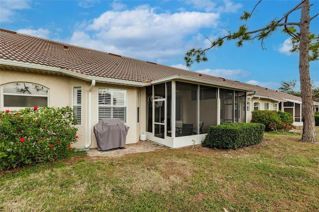 back of property featuring a lawn and a sunroom