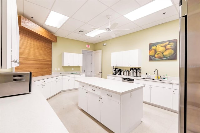 kitchen with white cabinets, a paneled ceiling, and sink