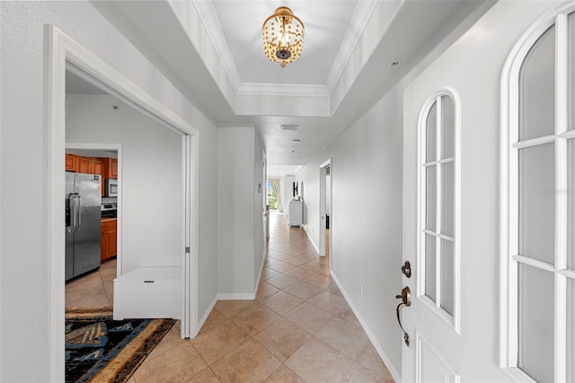 hall featuring a notable chandelier, ornamental molding, a raised ceiling, and light tile patterned floors