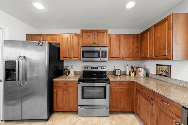 kitchen featuring light stone countertops, appliances with stainless steel finishes, and light tile patterned floors