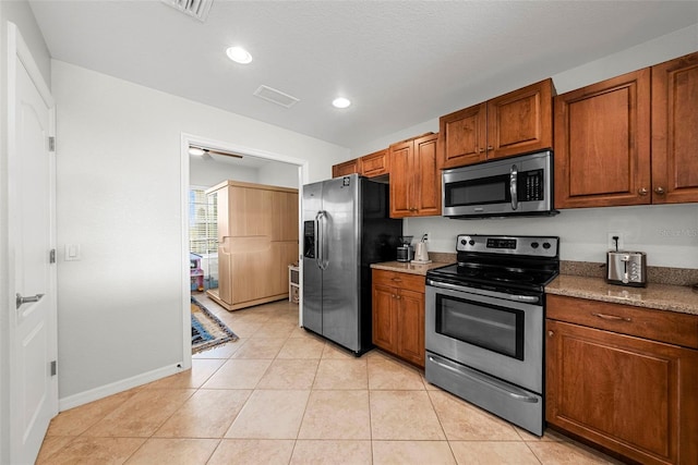 kitchen featuring light stone counters, light tile patterned flooring, and appliances with stainless steel finishes