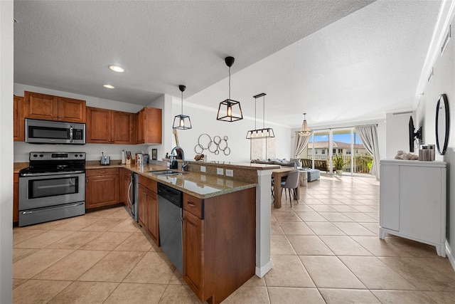 kitchen with pendant lighting, sink, appliances with stainless steel finishes, light stone counters, and kitchen peninsula