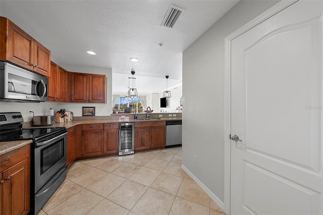 kitchen featuring wine cooler, sink, hanging light fixtures, a textured ceiling, and appliances with stainless steel finishes