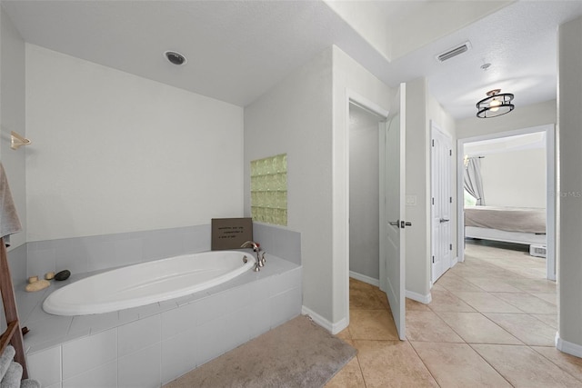 bathroom with tiled tub and tile patterned flooring