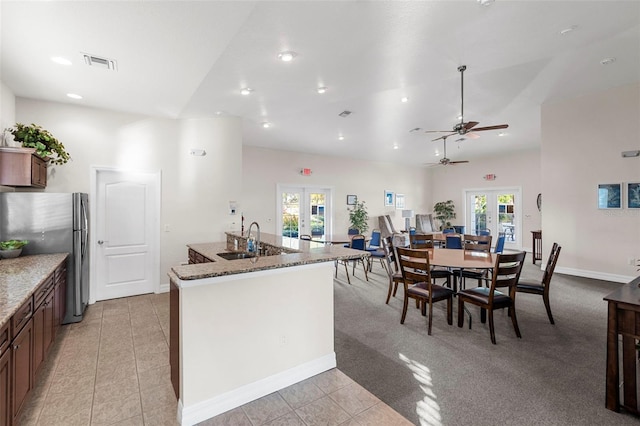 kitchen featuring french doors, stone counters, sink, and stainless steel refrigerator