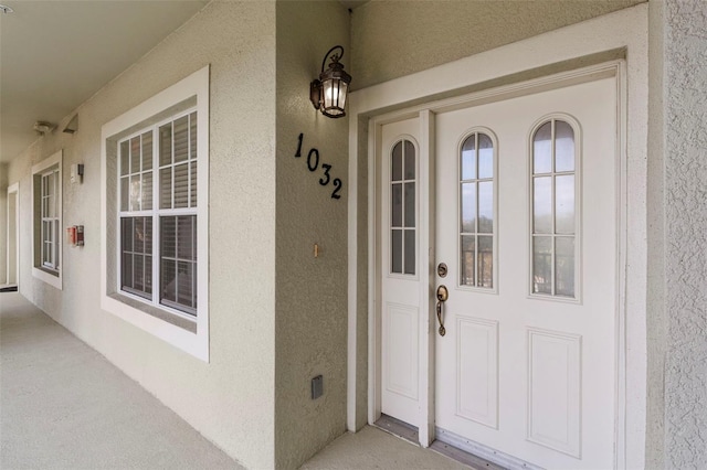 view of exterior entry with covered porch and stucco siding