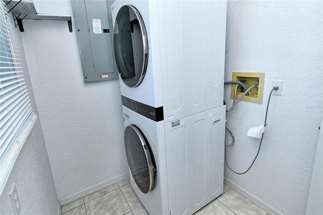 washroom with stacked washer and dryer, light tile patterned flooring, and electric panel