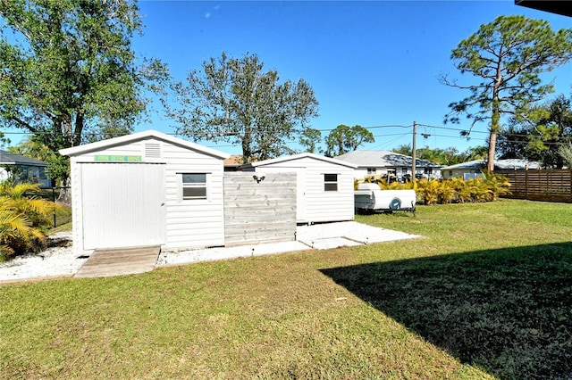 back of property featuring a storage unit and a lawn