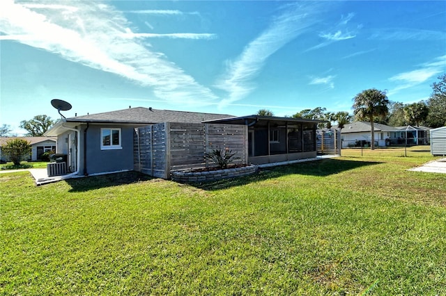 rear view of property featuring a sunroom, cooling unit, and a yard