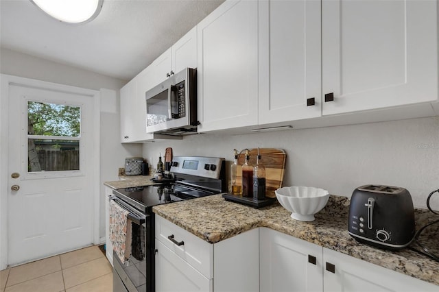 kitchen with light stone countertops, appliances with stainless steel finishes, light tile patterned flooring, and white cabinetry