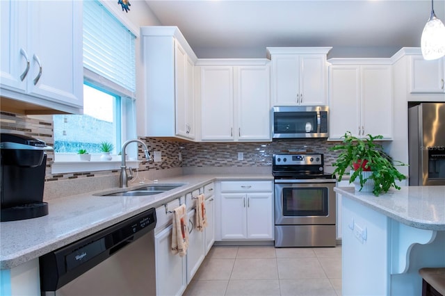 kitchen featuring pendant lighting, white cabinets, appliances with stainless steel finishes, sink, and light tile patterned flooring