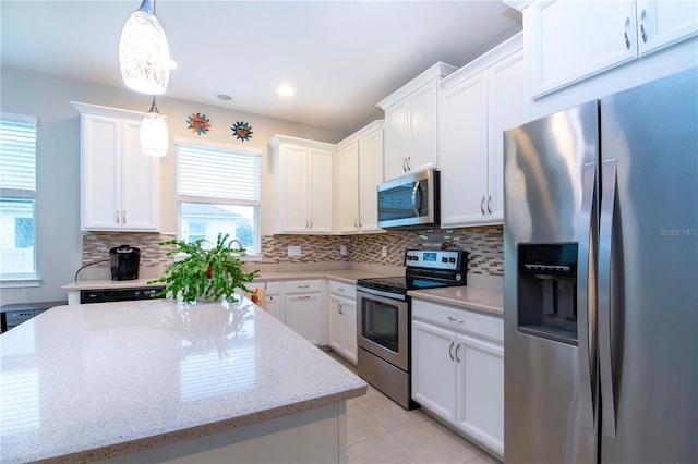 kitchen with decorative light fixtures, light stone countertops, white cabinets, and stainless steel appliances