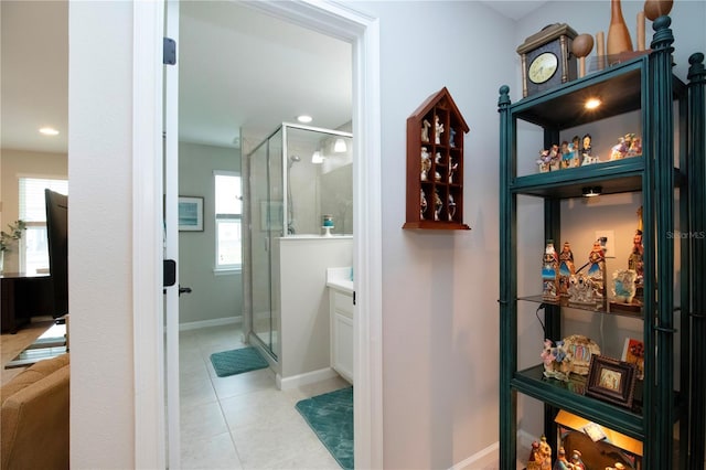 bathroom featuring a shower with shower door, a wealth of natural light, and tile patterned flooring