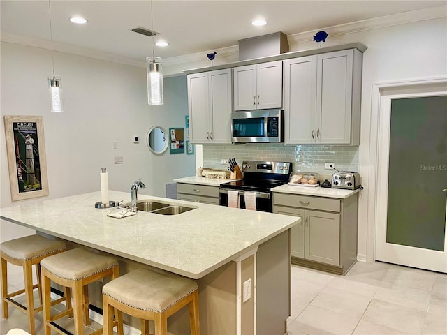 kitchen with stainless steel appliances, sink, gray cabinets, and an island with sink