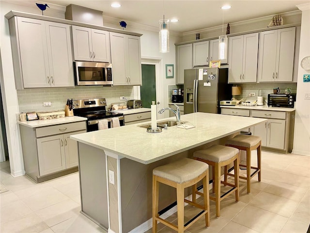 kitchen with sink, a center island with sink, gray cabinets, stainless steel appliances, and decorative backsplash